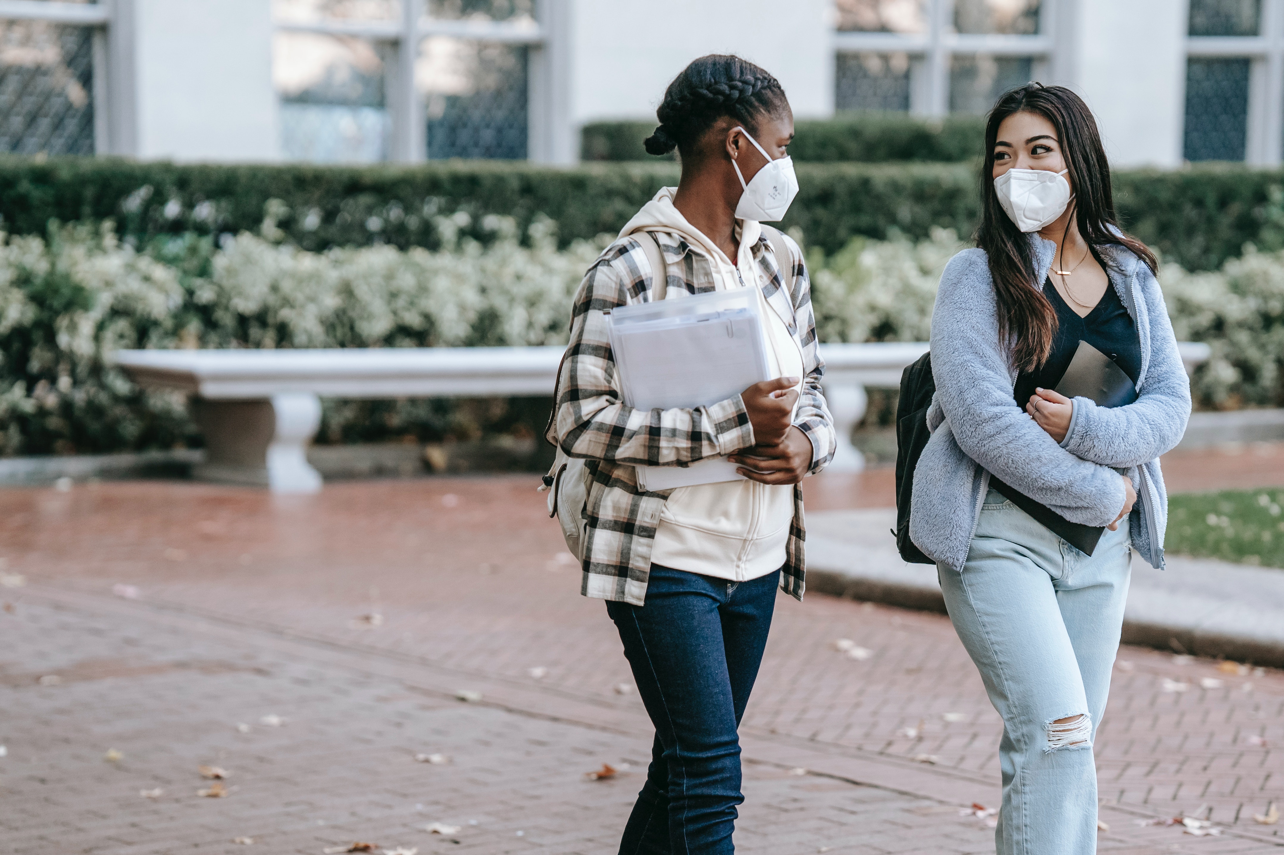 Two people walking outside together wearing face masks