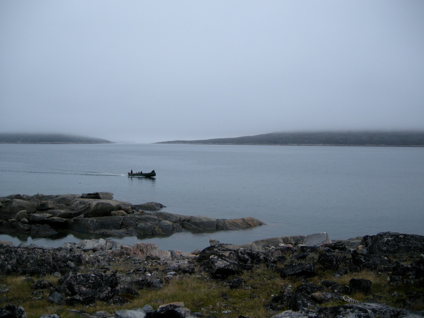 An Inuit family travelling by freighter canoe on a foggy summer day