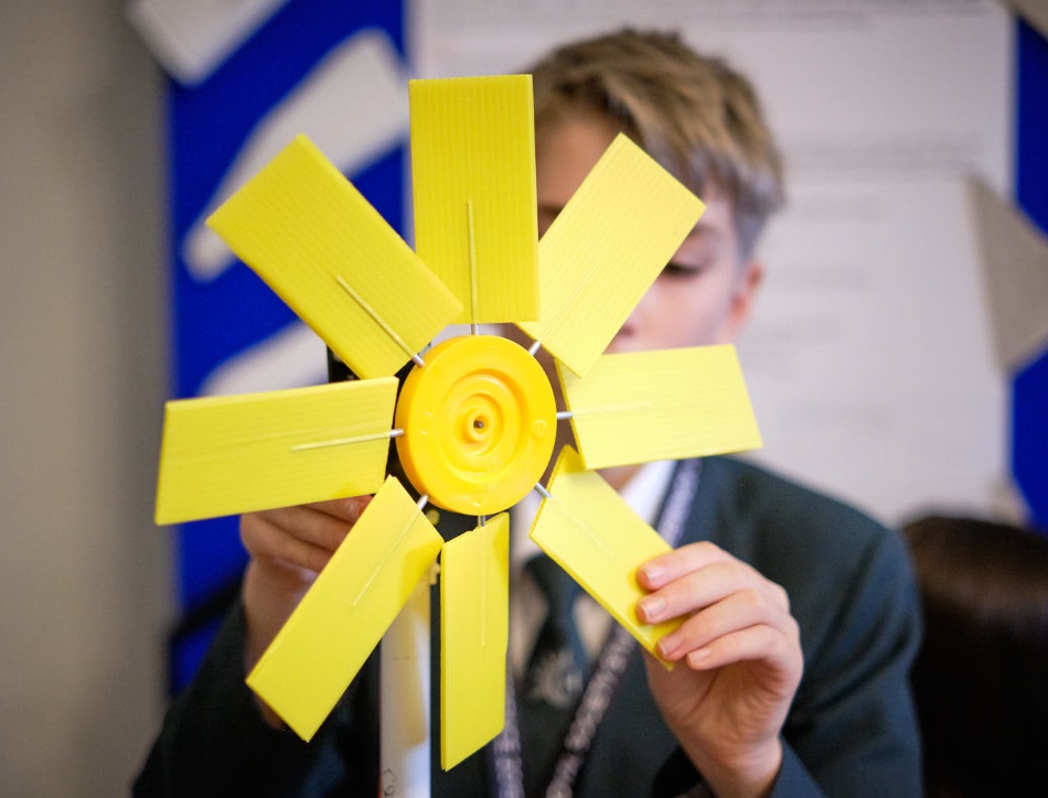 A child touches a Wind turbine from a Partnership Grant project