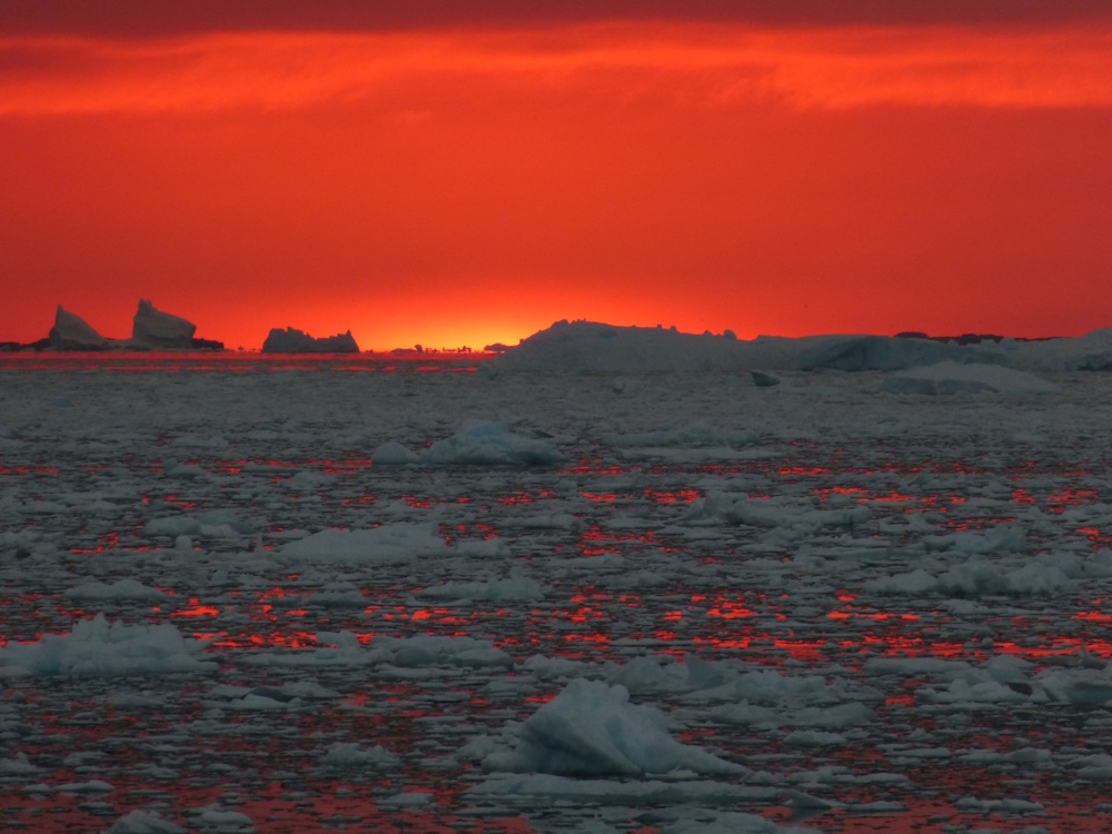 The sun, casting orange light over a polar horizon.