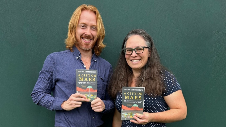 Kelly and Zach Weinersmith hold their book, A City on Mars