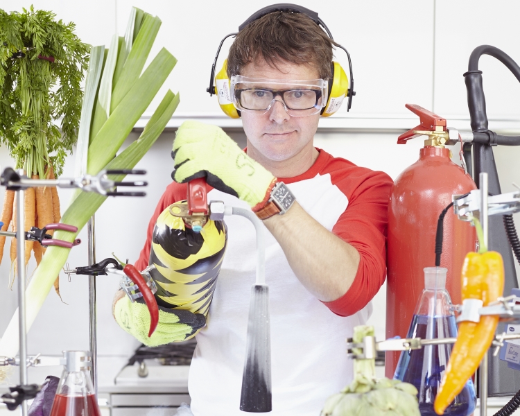Scientist in a lab holding a fire extinguisher surrounded by vegetables
