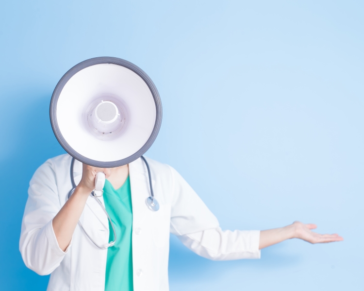 Female doctor in a white lab coat shouting into a megaphone