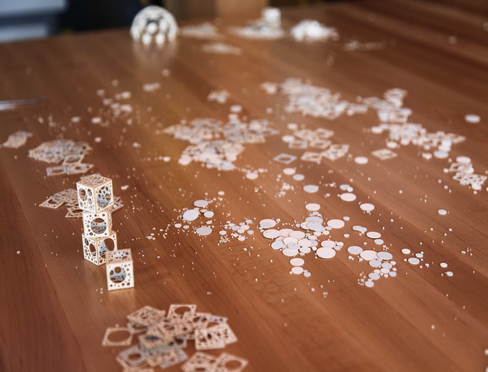 A table with miniature cubes made out of watercolour paper that have circles cut out of them and their debris