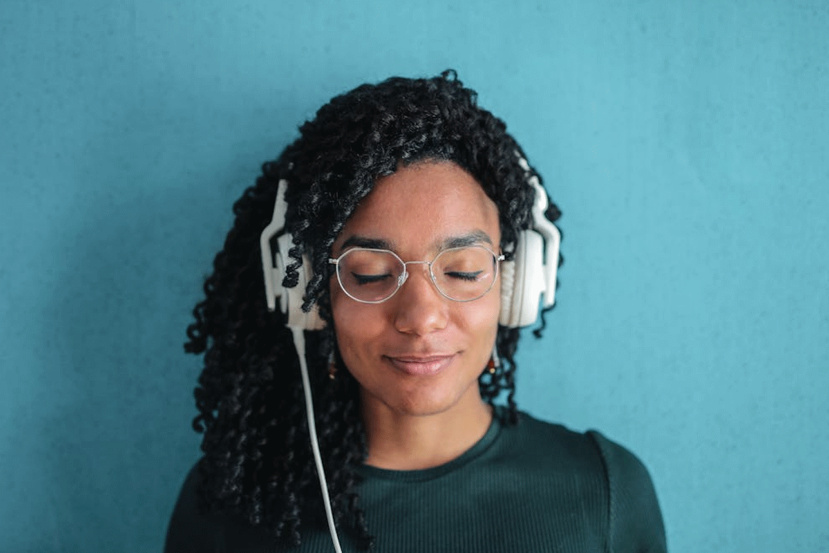 Portrait Photo of Smiling Woman in Black Top and Glasses Wearing White Headphones