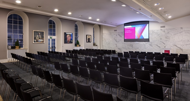 Rows of black chairs facing a projector screen.