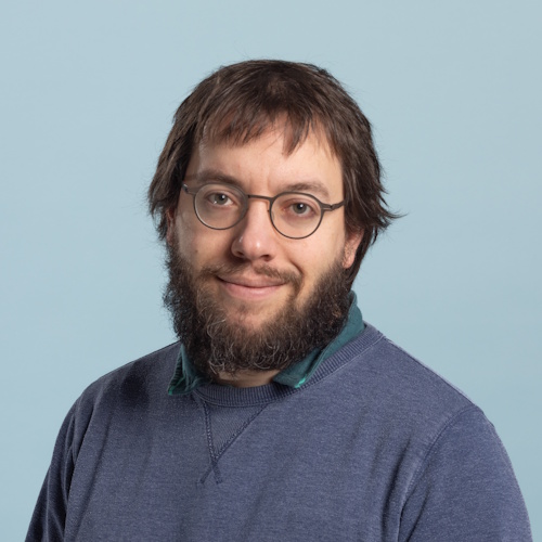 Jacob Aron wearing navy blue sweatshirt against a pale blue background